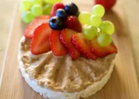 Granola Butter spread on a Rice Cake and garnished with Fruit