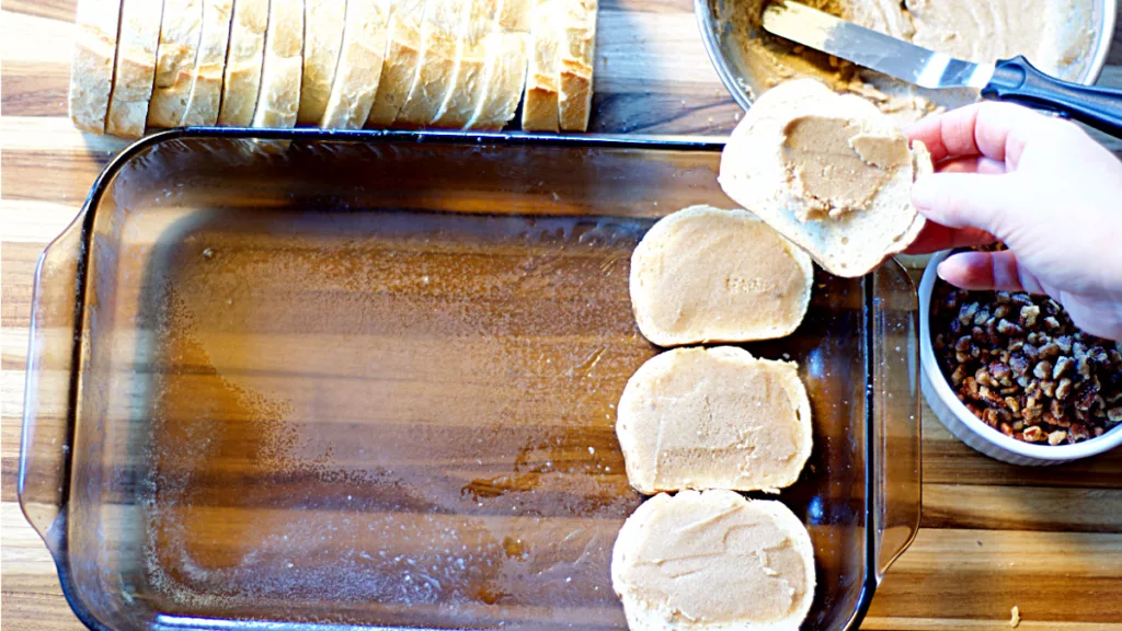 Pieces of bread, with sugary butter on them, placed in a baking dish