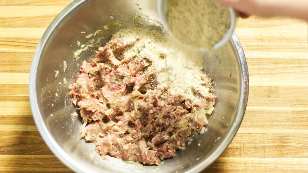 Meatloaf mixture with breadcrumbs being added.