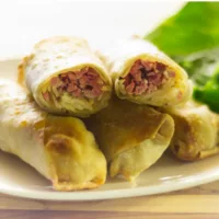 Plate of Reuben Egg Rolls with one cut open showing filling.