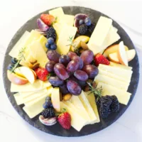 Round slate containing assorted Irish Cheddar cheeses, garnished with fruit.