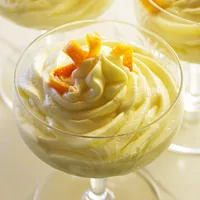 Orange Mousse in a glass dish garnished with a candied orange twist