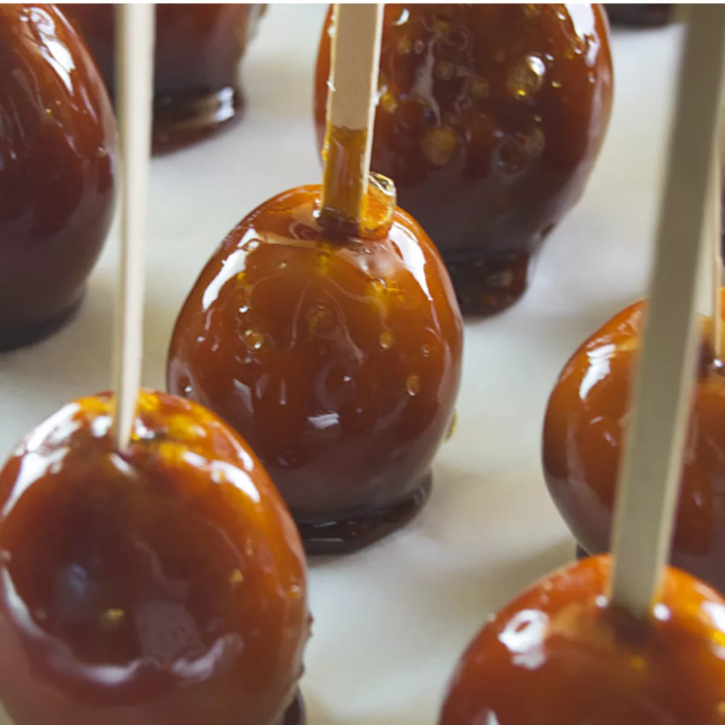 Completed Homemade Crab Apple Toffee Apples in a row on a sheet of wax paper.