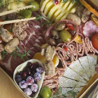 A selection of ingredients in the Grazing Box, cured meats, cheese, sugared cranberries, olives, spiced nuts and bamboo tongs.