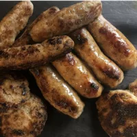 Plate plate containing 4 cooked Irish Pork Sausages with casing, 3 uncased sausage links and 4 sausage patties.