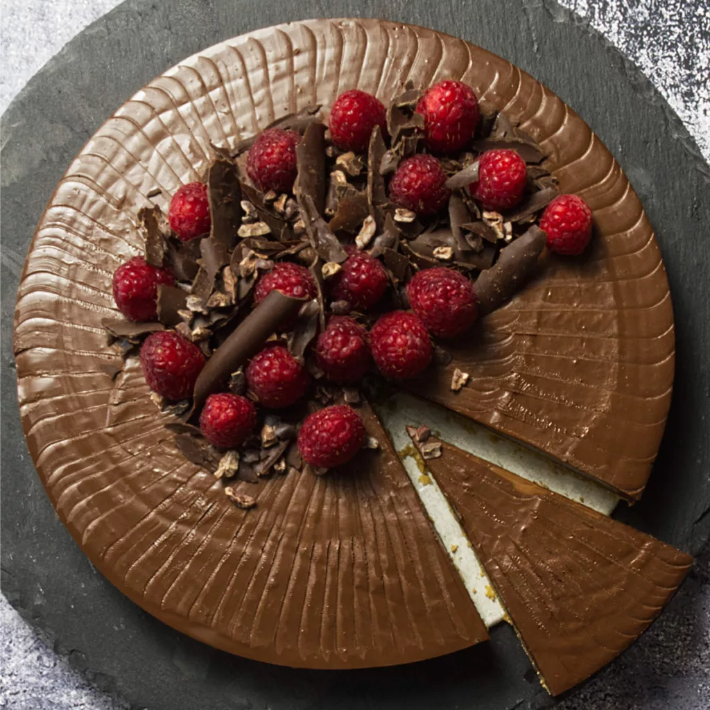 Chocolate Raspberry Tart on a black plate with a slice cut.