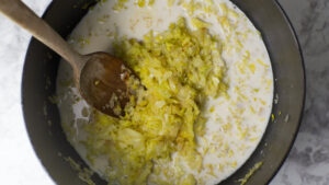 Sautéed cabbage and onions in a pot, milk is added.