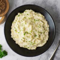 Black bowl containing Colcannon garnished with parsley.