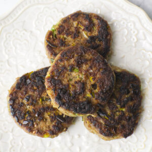 Four slices of cooked Vegetable Roll on a patterned white plate.