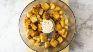 Croutons in a food processor bowl before being pulverized.