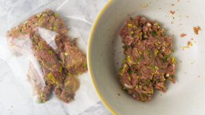 On the right is half of the sausage mixture in a bowl and on the left is the other half of the sausage mixture in a plastic bag.