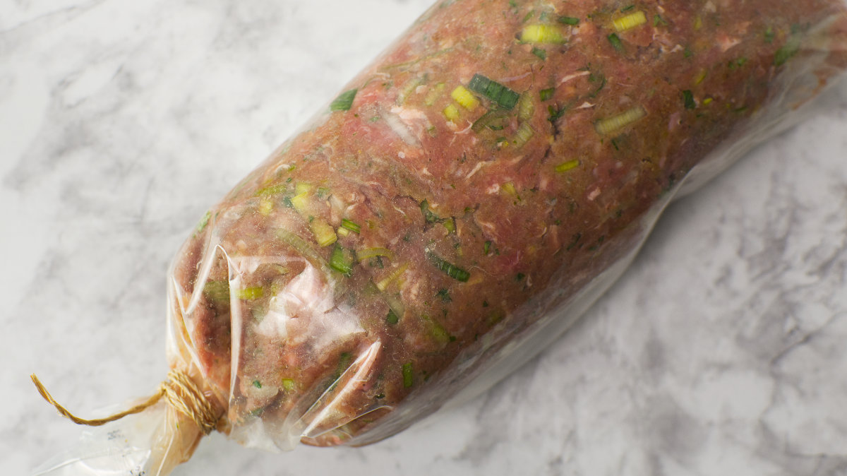Uncooked Vegetable Roll in a plastic bag formed into a sausage shape, tied at one end.