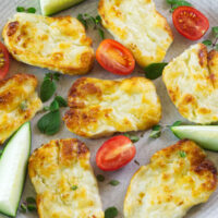 Crispy air fryer Halloumi on a plate decorated with cherry tomatoes, cucumber wedges and fresh oregano.