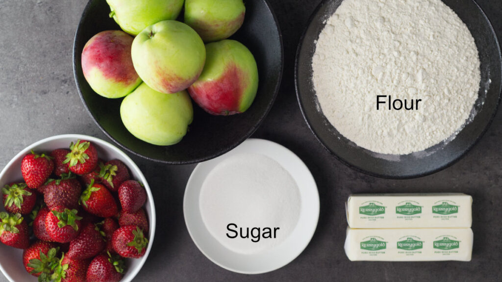 Ingredients needed to make Apple Strawberry Crumble - apples, flour, butter, sugar and strawberries.