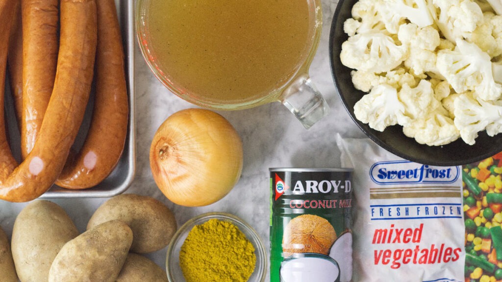 Ingredients used to make Slow Cooker Curried Sausages - Smoked sausages, stock, cauliflower, frozen mixed vegetables, coconut milk, onion, curry powder and potatoes.