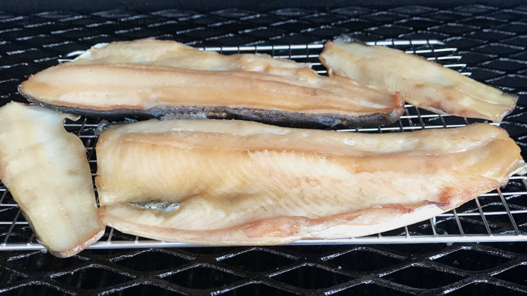 Filleted trout being smoked in a pellet grill. The trout fillets have taken on color.
