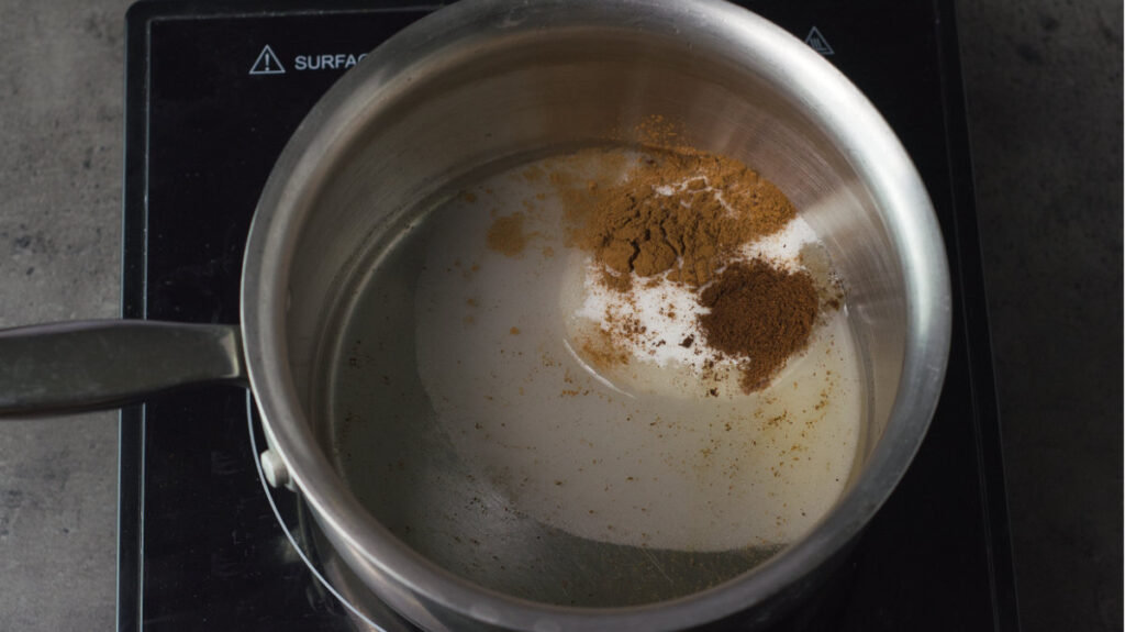 Pot containing sugar, water and spices on a burner.