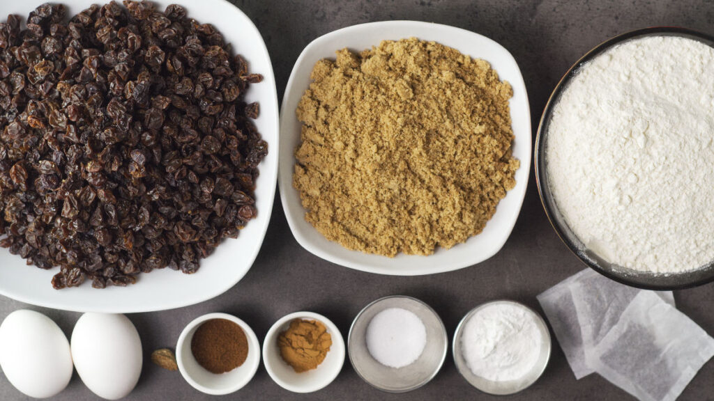Ingredients needed to make Irish Tea Loaf - raisins, brown sugar, gluten free flour, eggs, nutmeg, cinnamon, clove, salt, baking powder, tea.