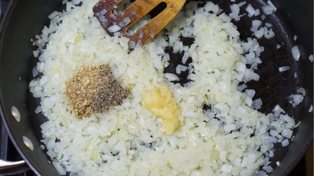 Grated garlic, and ground coriander are added to the sautéed onion.