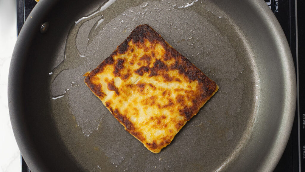 Fried square Potato Farl in a frying pan.