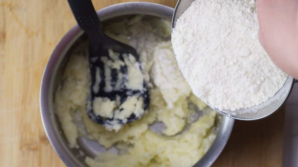 Pot of mashed potatoes with flour being added.