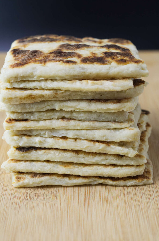 Stack of square Potato Farls on a wooden board.