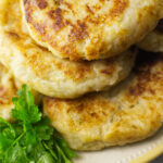 Close up image of three Colcannon Cakes on a plate with a garnish of parsley sprigs.